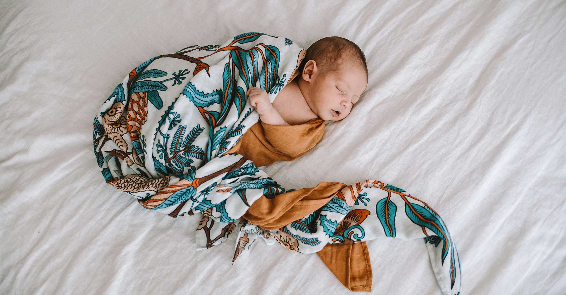 One month old baby girl swaddled in a beige wrap.